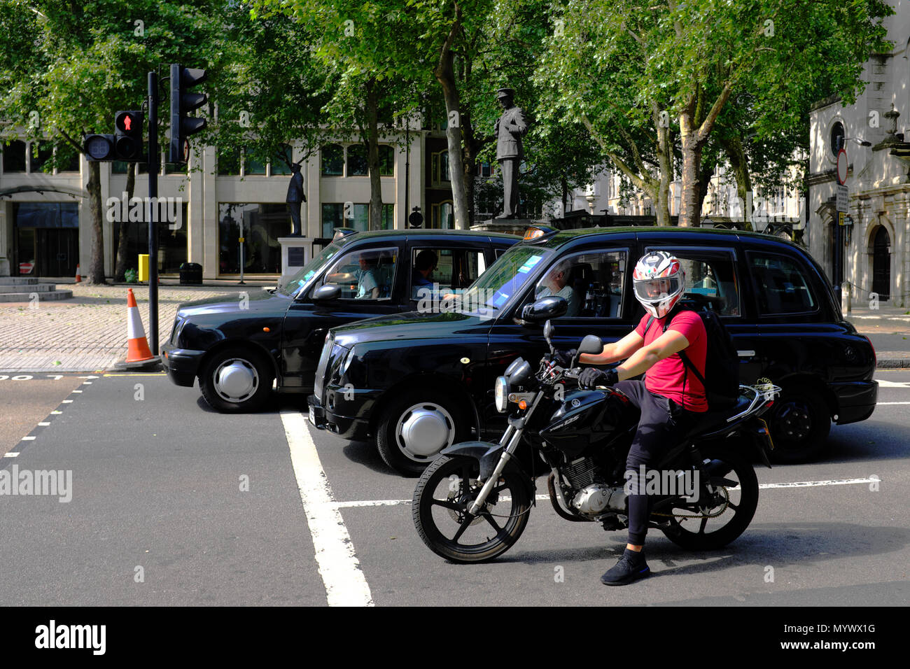 Moto e i Taxi in attesa di un semaforo, London, England, Regno Unito Foto Stock