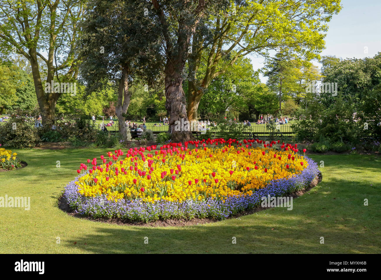Coloratissime aiuole di fiori in un parco del Regno Unito con persone relax su una giornata suuny. Foto Stock