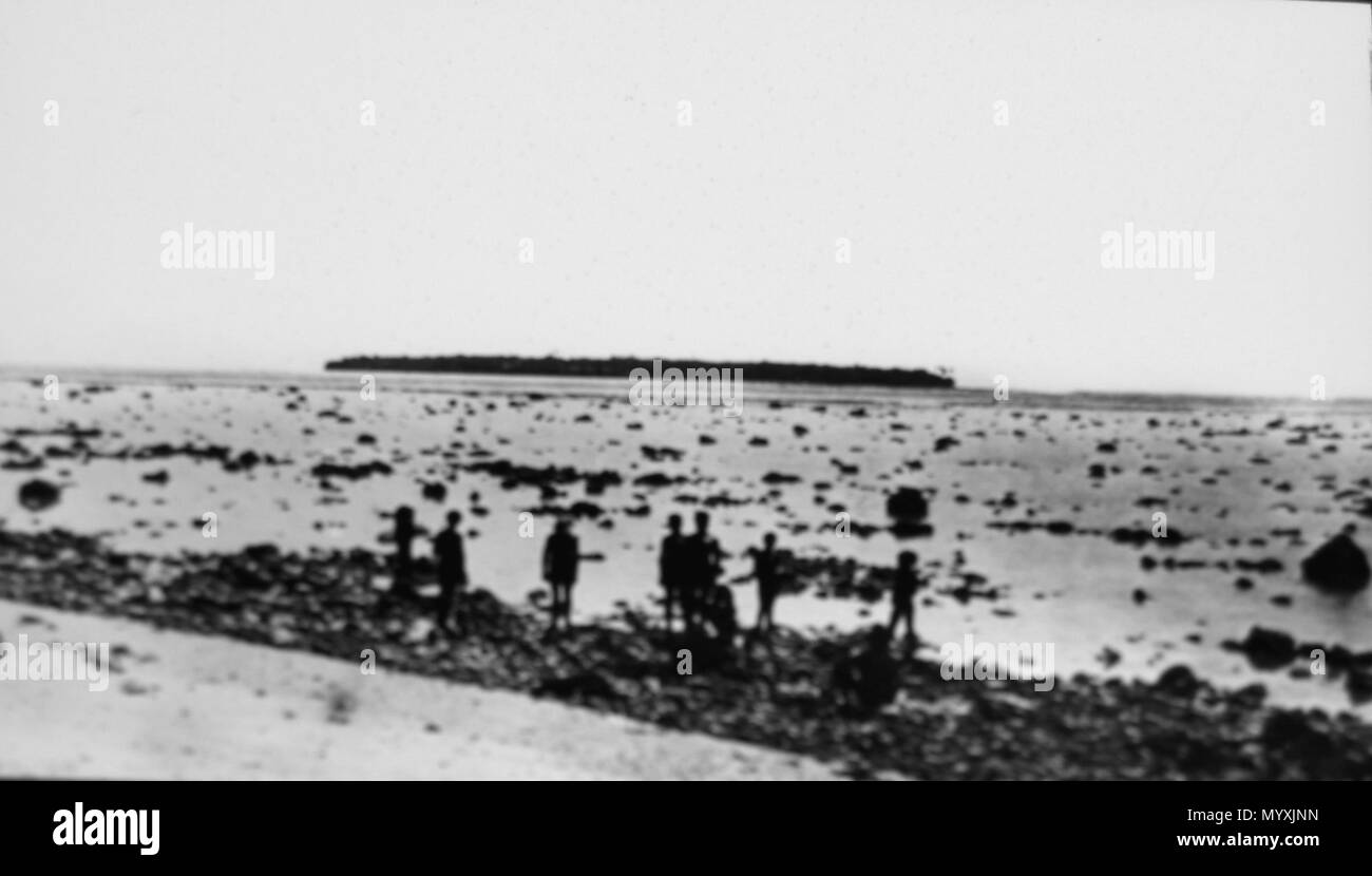 . Inglese: Coral reef e un groop di gente del posto. Più lontano, Fana isola. Français : Vue d'onu récif de corail devant l'île de Sonsorol ; groupe autochtone; dans l'arrière-piano île de Fanna. . 9 maggio 2007, 00:45:42. Georg Thilenius 1 Fana isola da Sonsorol Island (1908-1910) Foto Stock