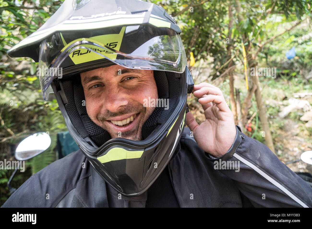 Un maschio felice motociclista che indossa un casco Foto Stock