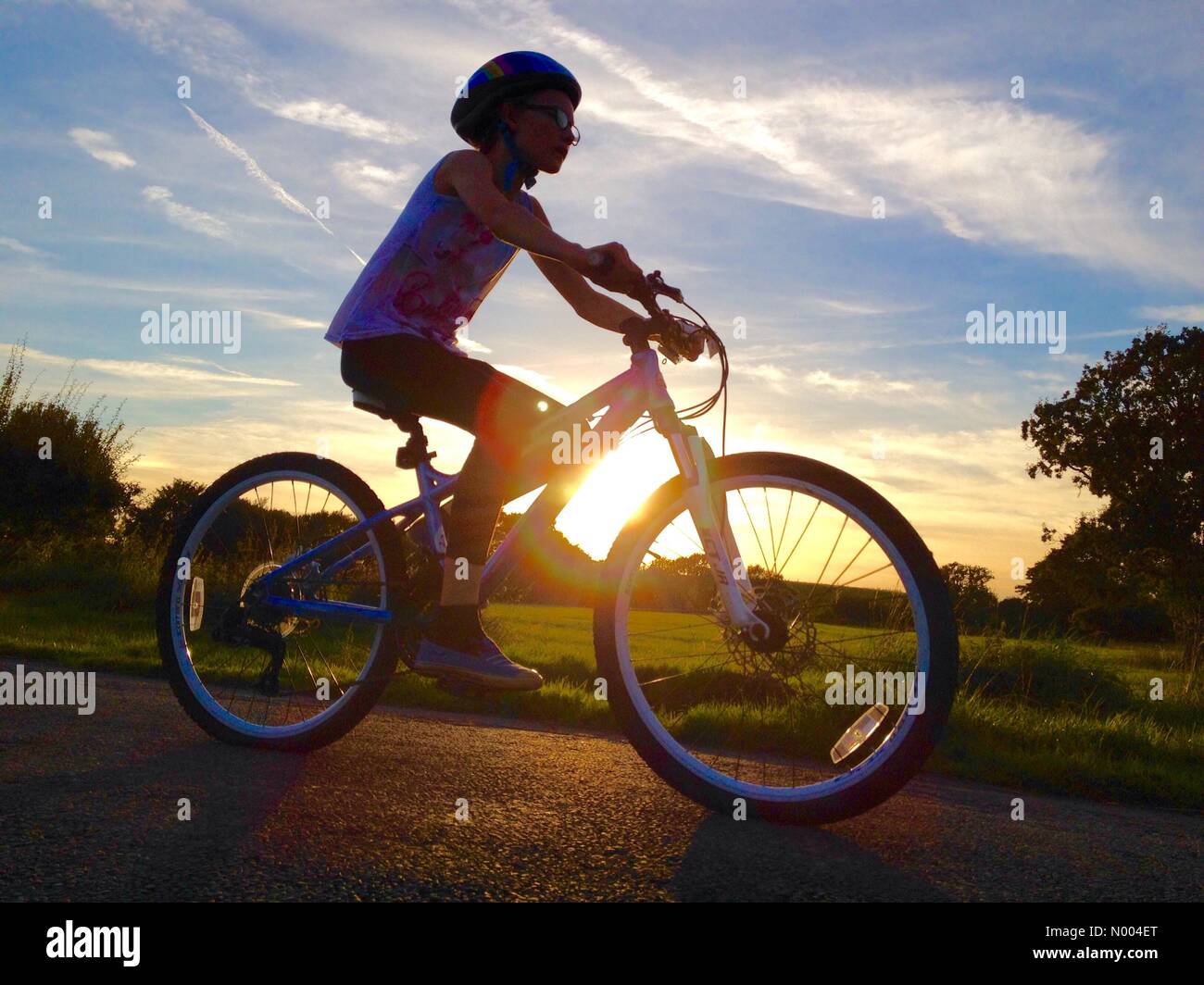 Regno Unito meteo domenica 27 settembre Adlington in Lancashire. Ragazza giovane cicli alla fine di una bella giornata autunnale come il sole comincia a impostare Foto Stock