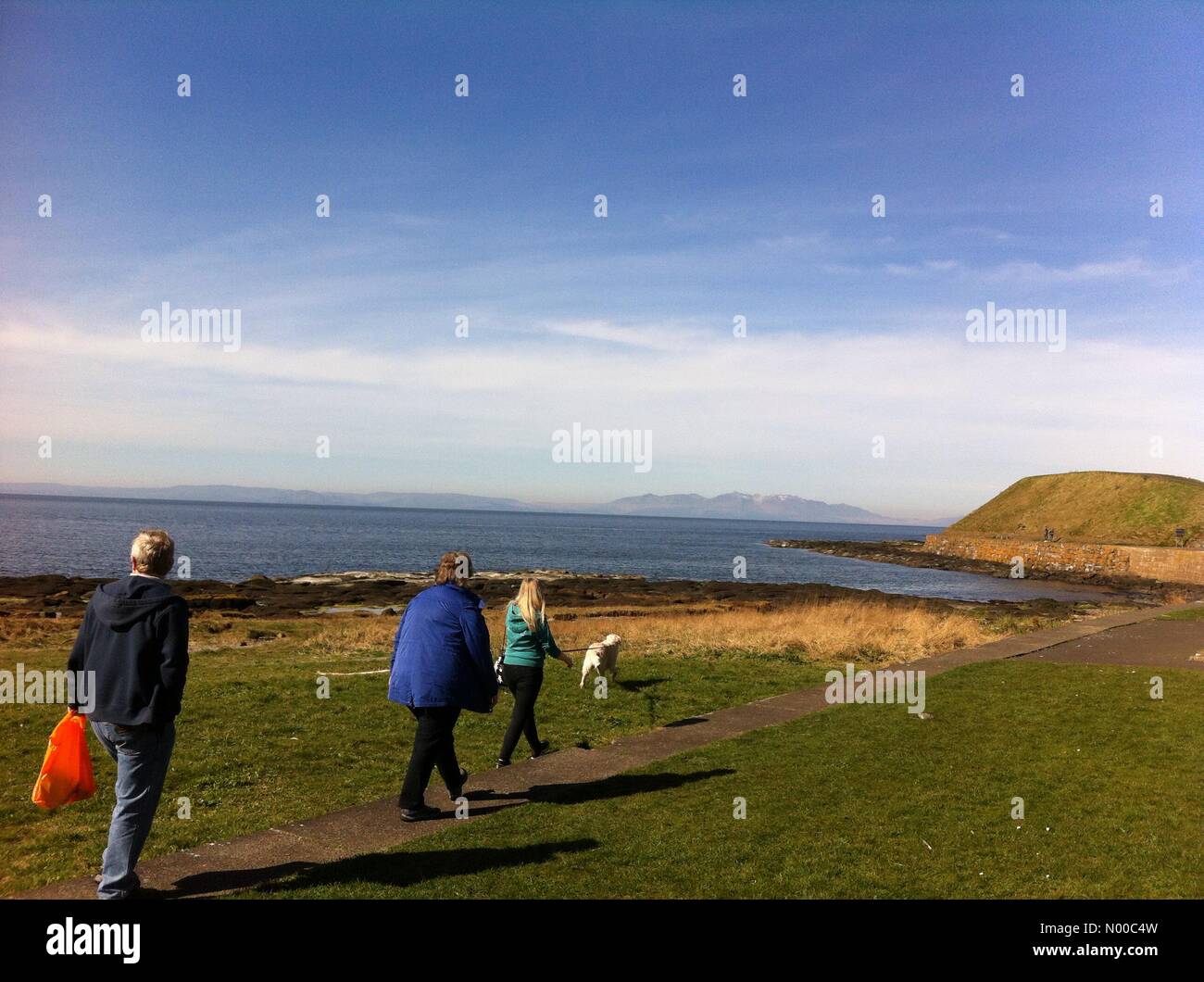 Troon, Regno Unito. 26 Mar, 2017. Troon, Regno Unito . Il 23 marzo 2017. Dog walkers godere della vista di Snow capped capra cadde sull'isola di Arran dalla costa a Troon, Scozia sulle madri giorno. Credito: Alan/StockimoNews/Alamy Live News Foto Stock