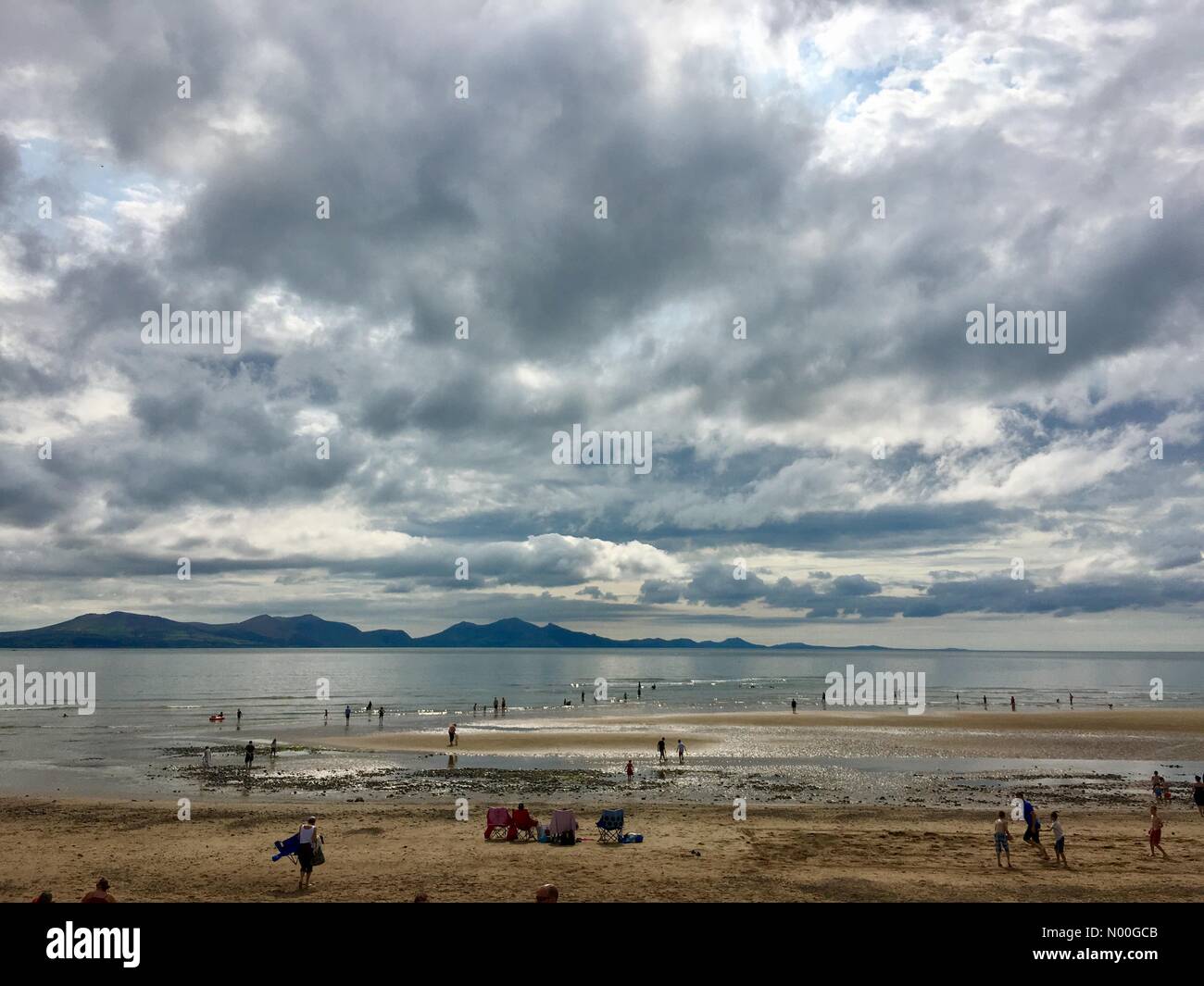 Regno Unito: Meteo soleggiato ma giorno nuvoloso su Anglesey. Famiglie godendo un nuvoloso ma calda giornata sulla spiaggia di Newborough. Foto Stock