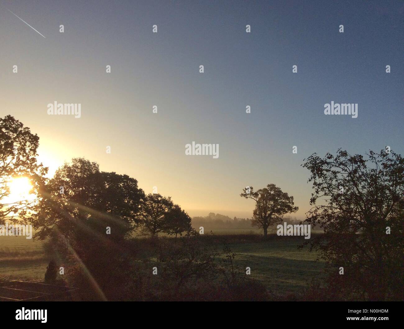 Meteo nel Regno Unito: Il sole della mattina presto splende attraverso la nebbia sui campi nel South Staffordshire. Foto Stock