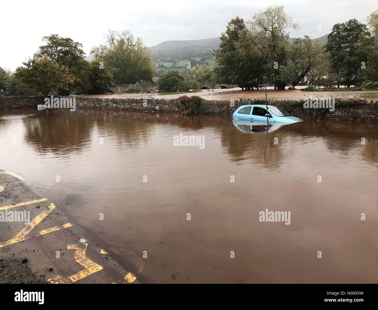 Regno Unito - Previsioni del tempo - Le inondazioni a Crickhowell Galles - Sabato 13 Ottobre 2018 - Un auto abbandonate sommerso in un parcheggio adiacente al fiume Usk dopo piogge torrenziali e le inondazioni in Galles. Foto Stock
