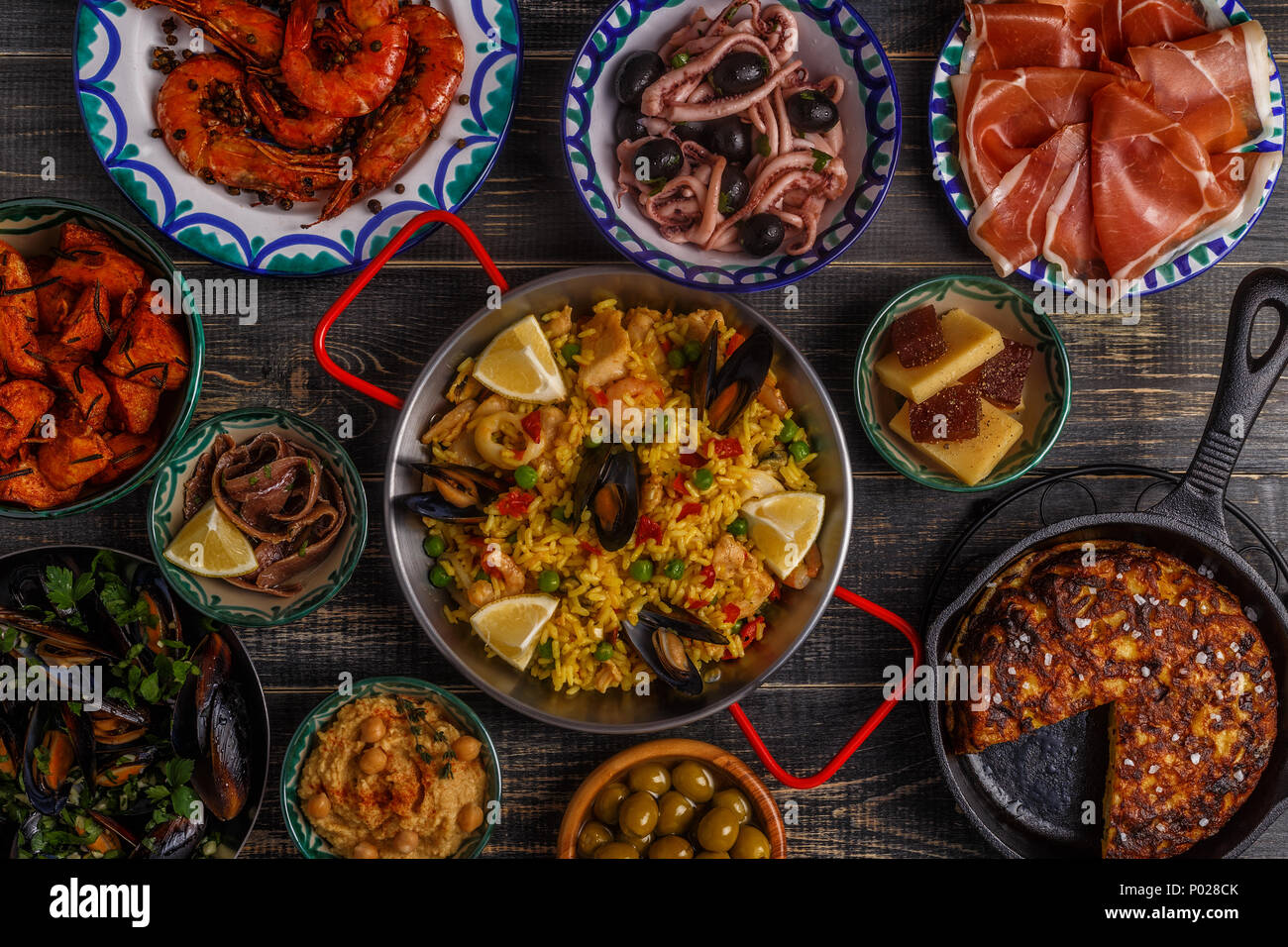 Tipiche tapas spagnole concetto. Concetto includono fette di prosciutto, bocce con olive, acciughe, piccante di patate purea di ceci, gamberi, calamari, manche Foto Stock