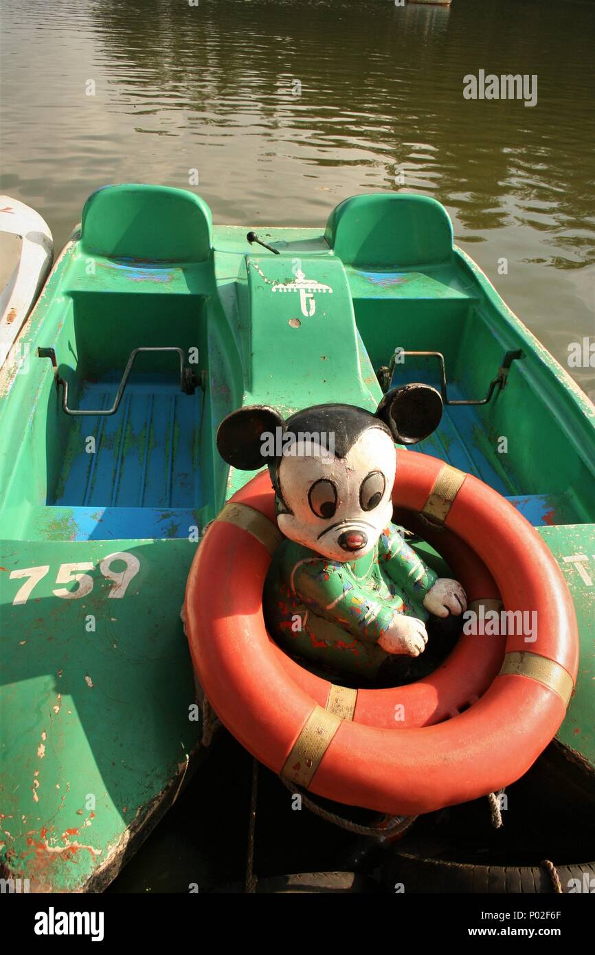 Vecchio usurato barca verde con retro Mickey Mouse la figura e la vita anelli, Ooty, Tamil Nadu, India Foto Stock