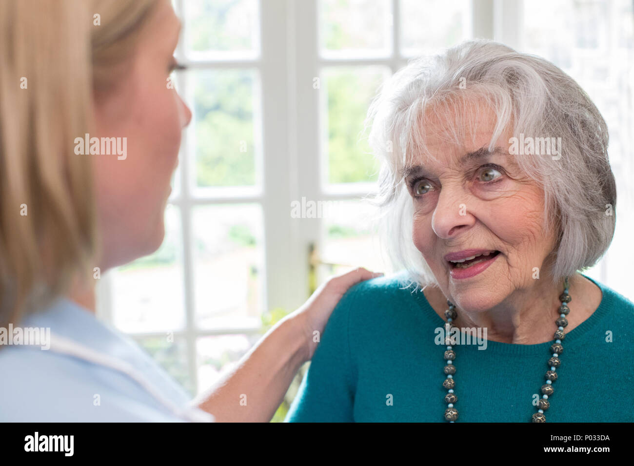 Lavoratore di cura di parlare alla donna Senior a casa Foto Stock
