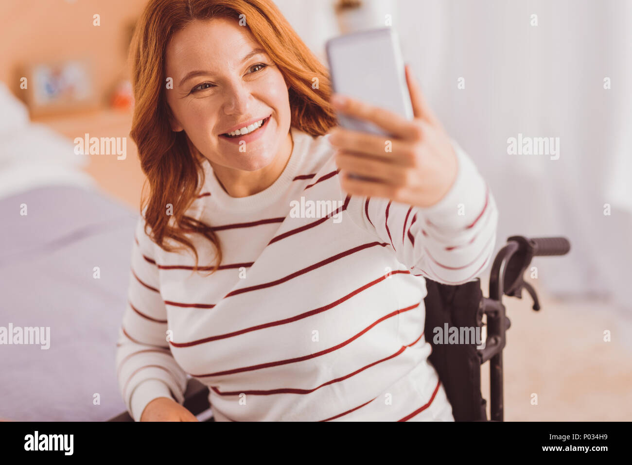 Express positività. Affascinante persona femmina alzando il braccio sinistro mentre guardando il suo gadget Foto Stock