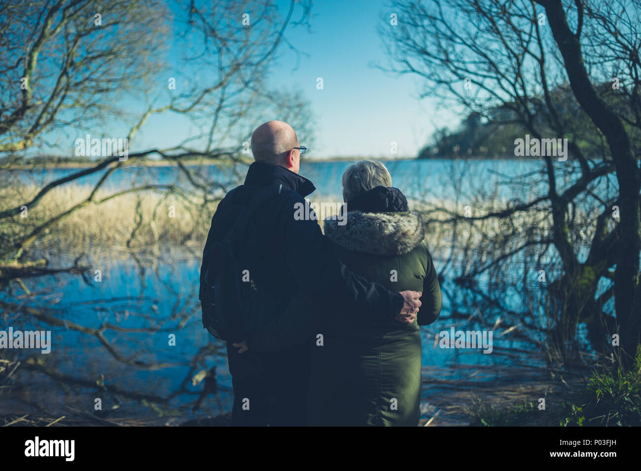 Una coppia senior godendo il pensionamento da un lago in inverno Foto Stock