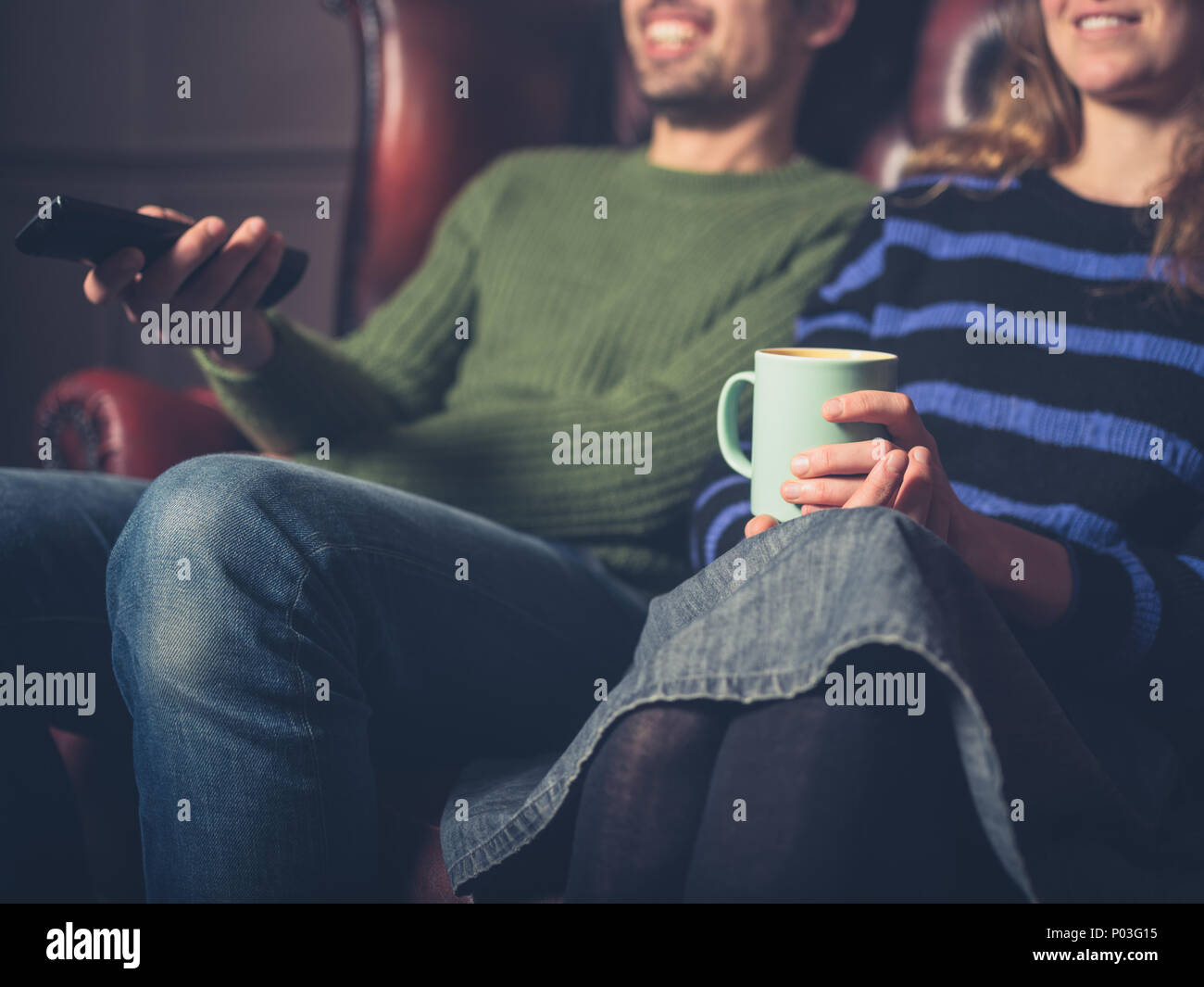 Una felice coppia giovane su un divano a guardare la televisione Foto Stock