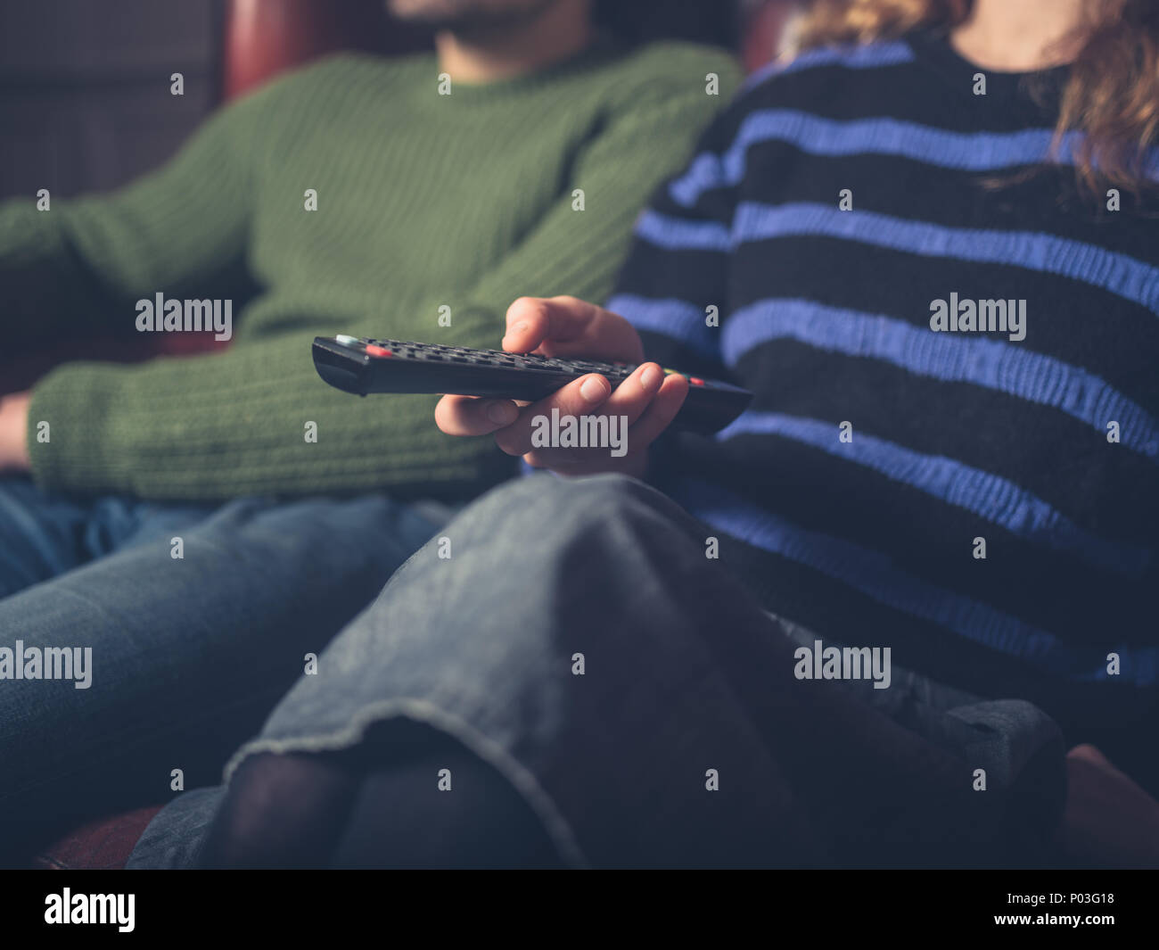 Una giovane coppia su un divano a guardare la televisione Foto Stock