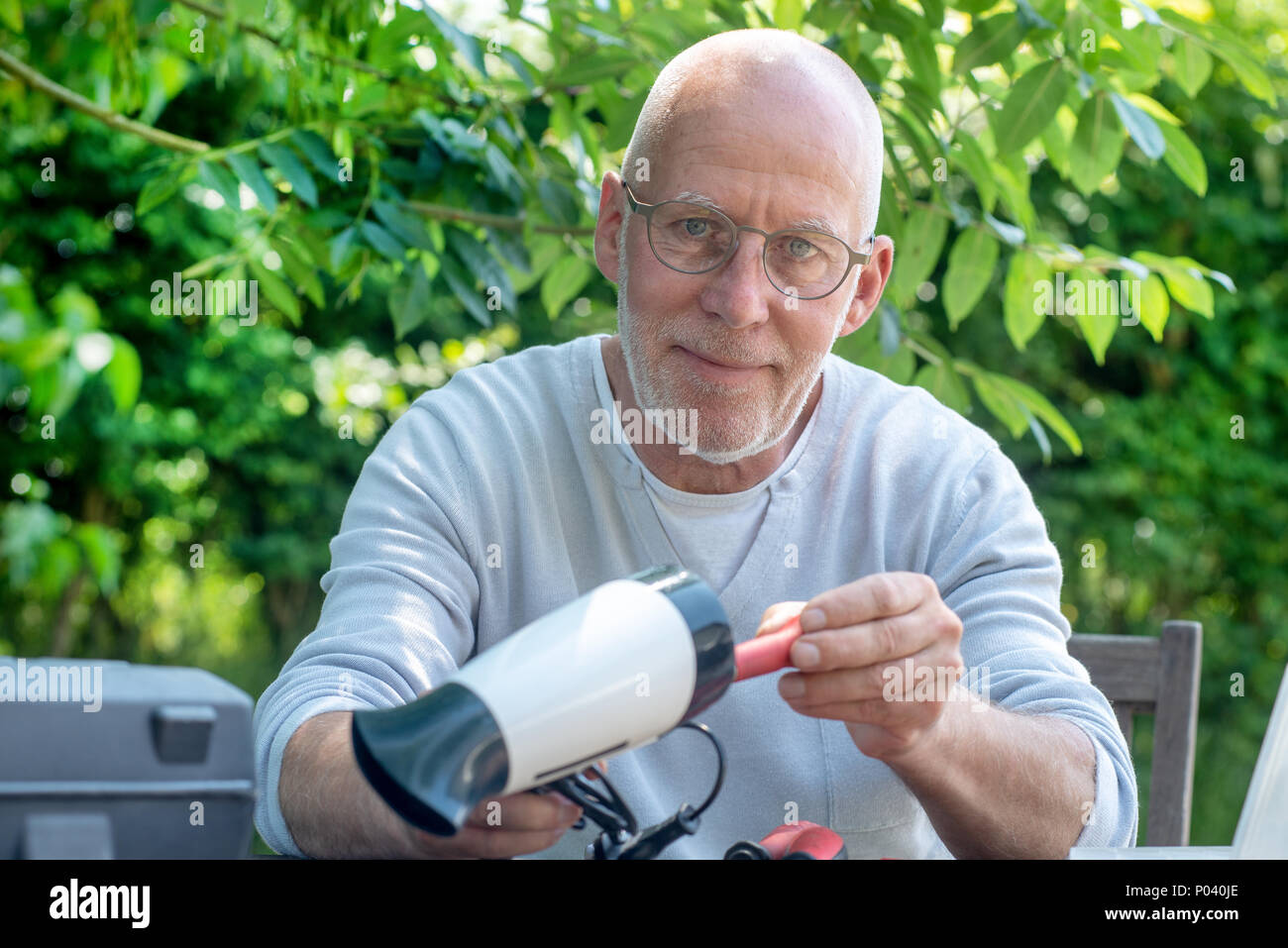 Un uomo che ripara un asciugacapelli per donna Foto Stock