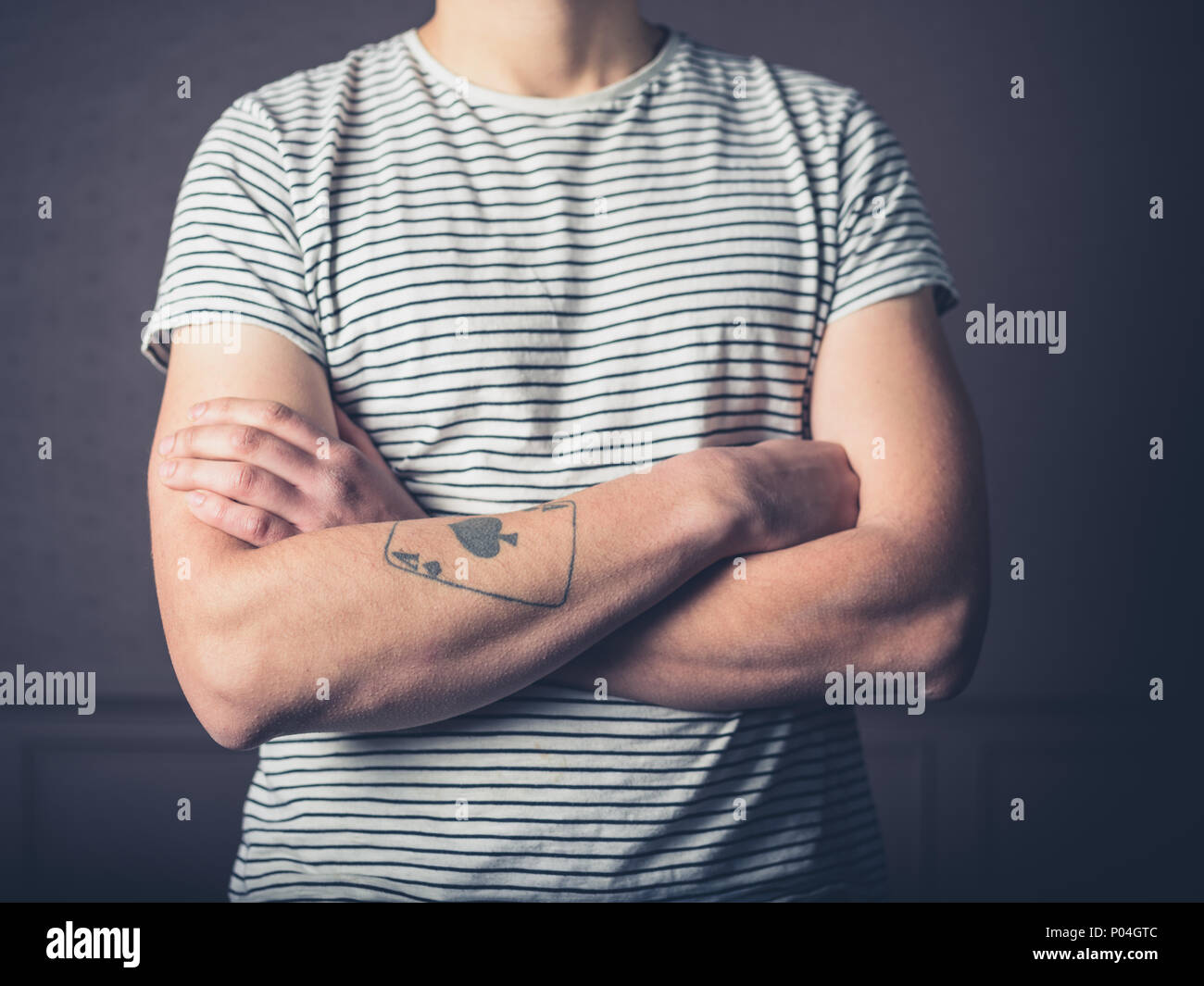 Un giovane uomo con un tatuaggio è attraversando le sue braccia Foto Stock