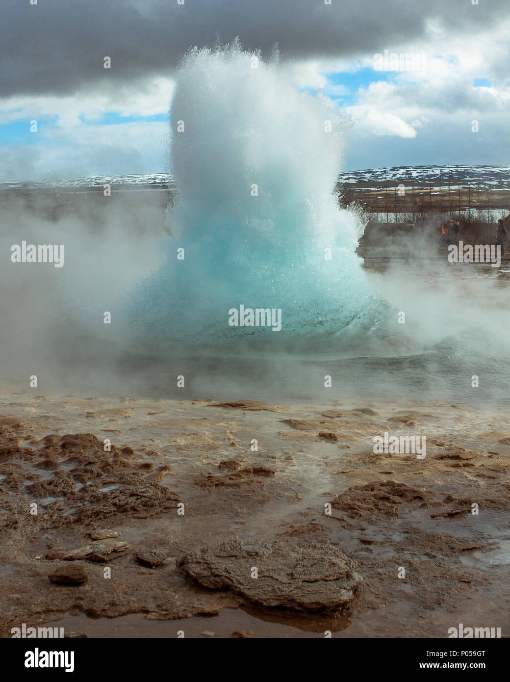 L'Islanda, il grande geyser esplodere con lontane montagne coperte di neve in background Foto Stock