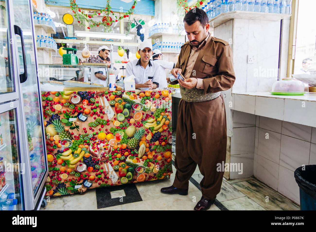 Dohuk, Dohuk Governatorato, regione del Kurdistan in Iraq : un uomo curdo in costume regionale si colloca a una gelateria nella capitale provinciale di Doh Foto Stock