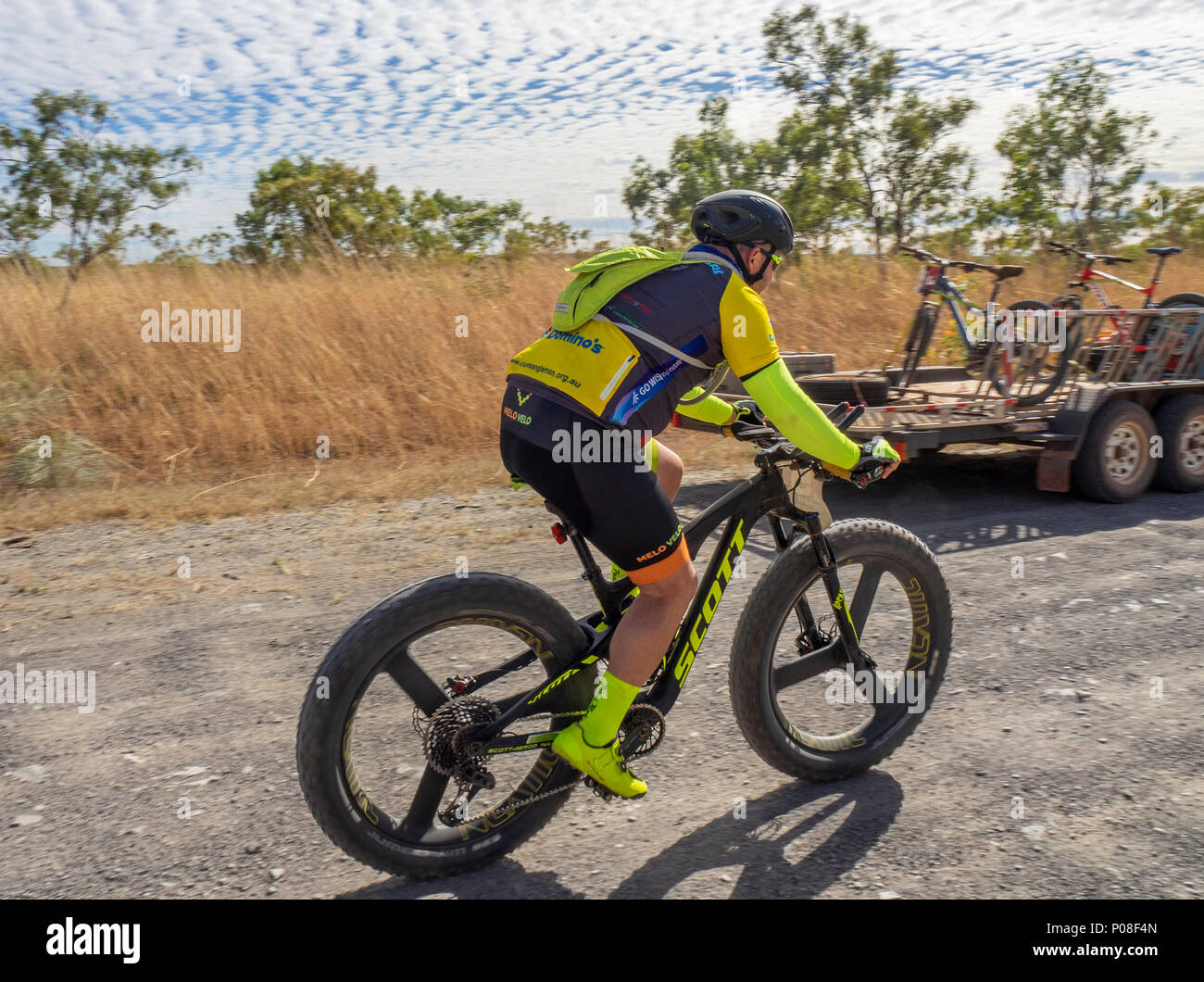 Un Gibb Challenge 2018 ciclista passato a cavallo di un veicolo di supporto e rimorchio su sporco Gibb River Road WA Kimberley Australia. Foto Stock