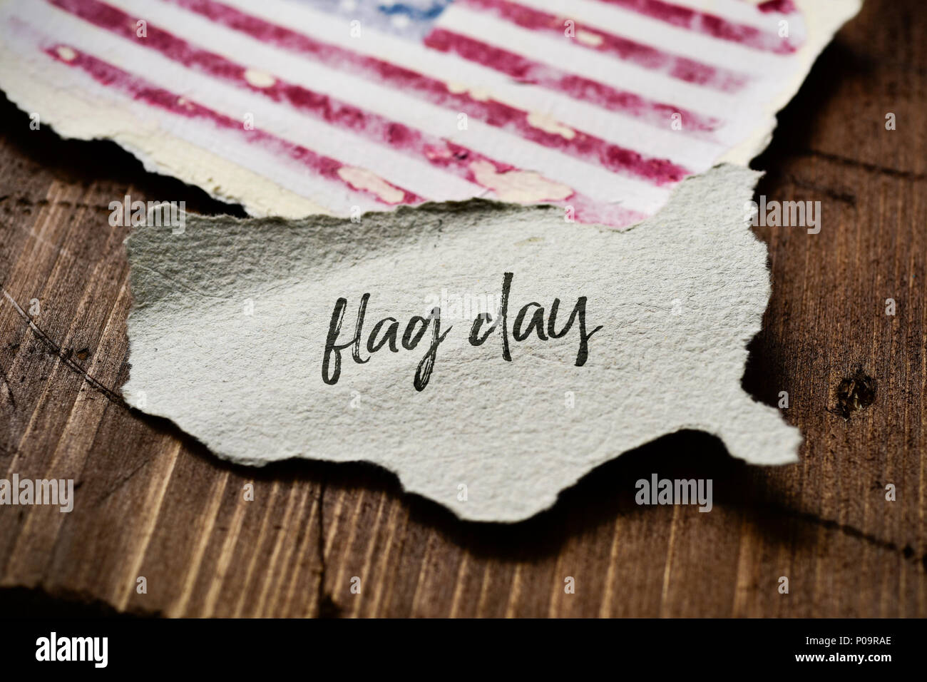 Primo piano di un pezzo di carta a forma di gli Stati Uniti con il testo Giornata di bandiera scritto in esso e una bandiera degli Stati Uniti, su un rustico di una superficie di legno Foto Stock