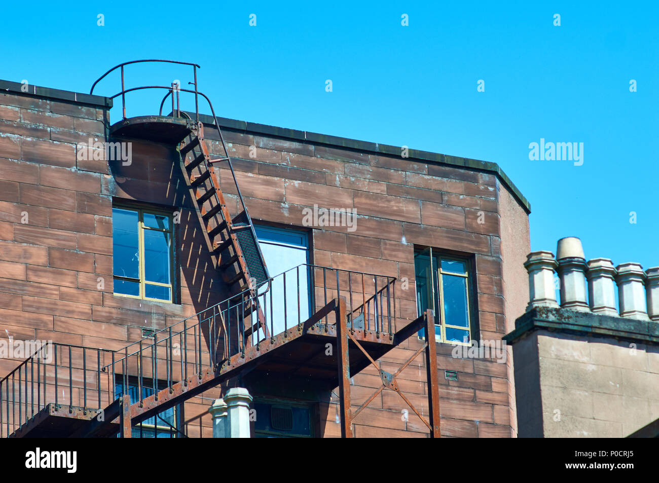 Accesso tetto scale di metallo su un vecchio edificio in pietra arenaria a Glasgow, UK. Foto Stock