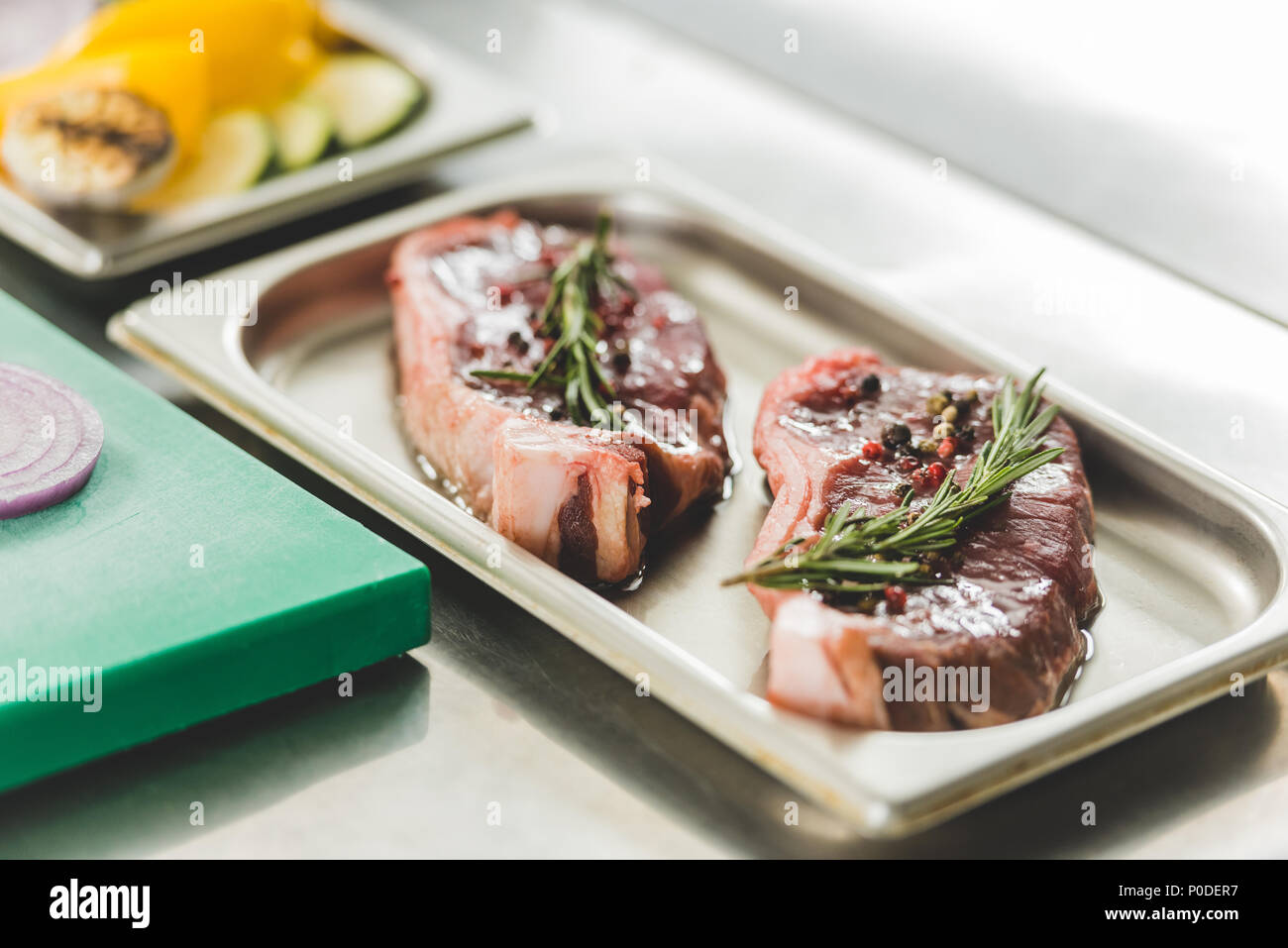 Carne cruda con erbe e olio sul vassoio sul tavolo Foto Stock