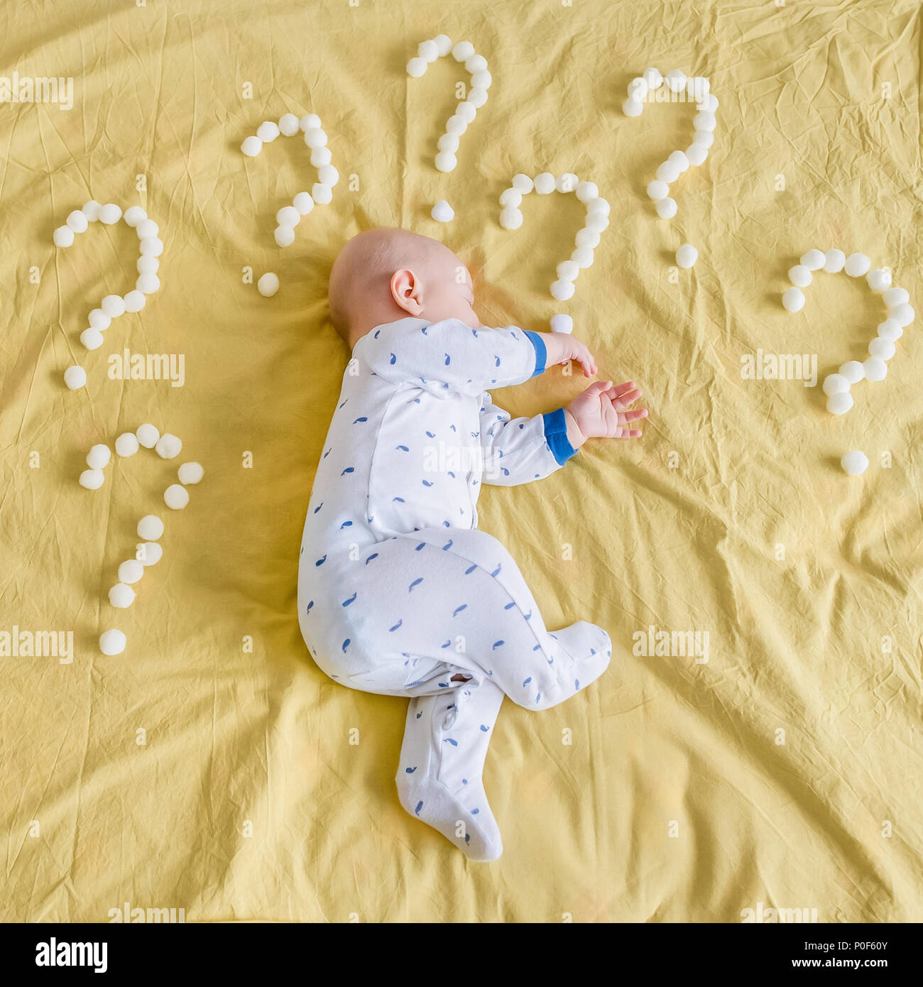 Vista superiore del neonato Bambino circondata con i punti di domanda fatta  di palline di cotone che dorme sul lato a letto Foto stock - Alamy