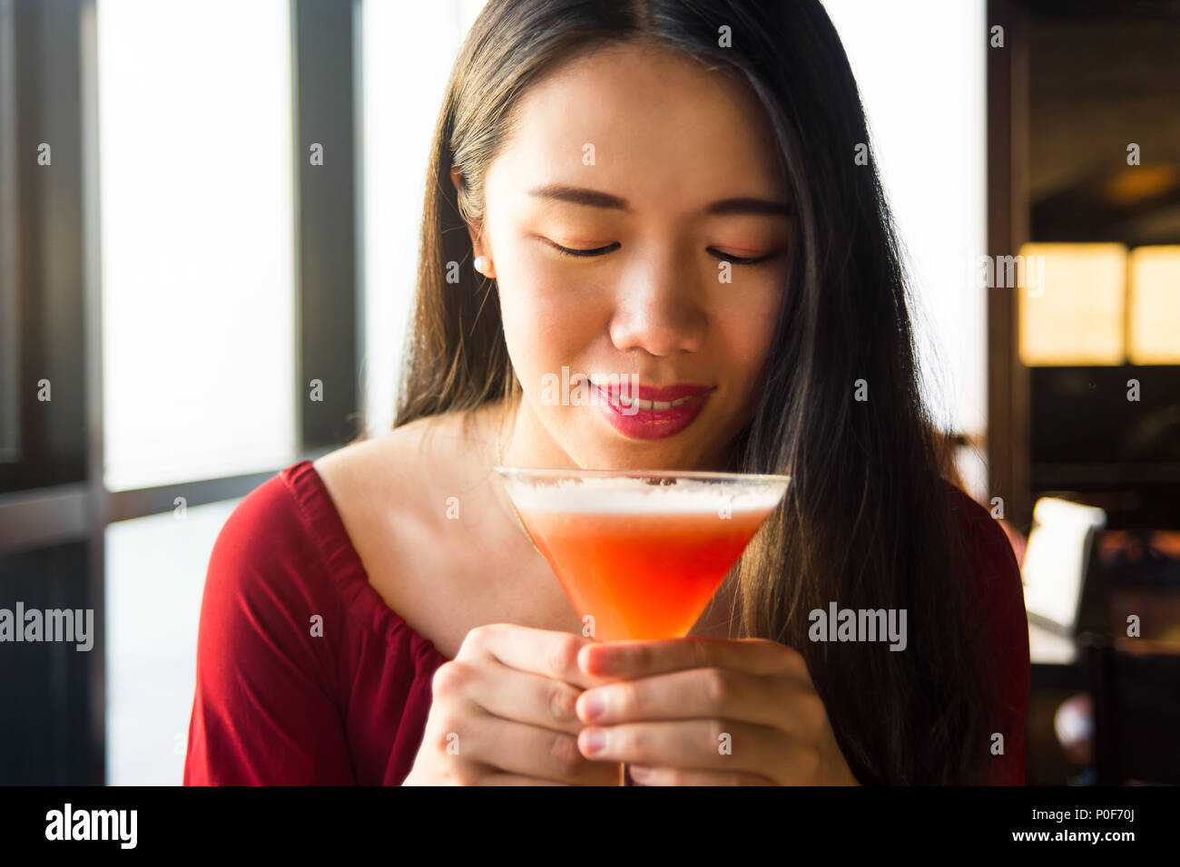 Ragazza asiatica avente un cocktail in un bar Foto Stock