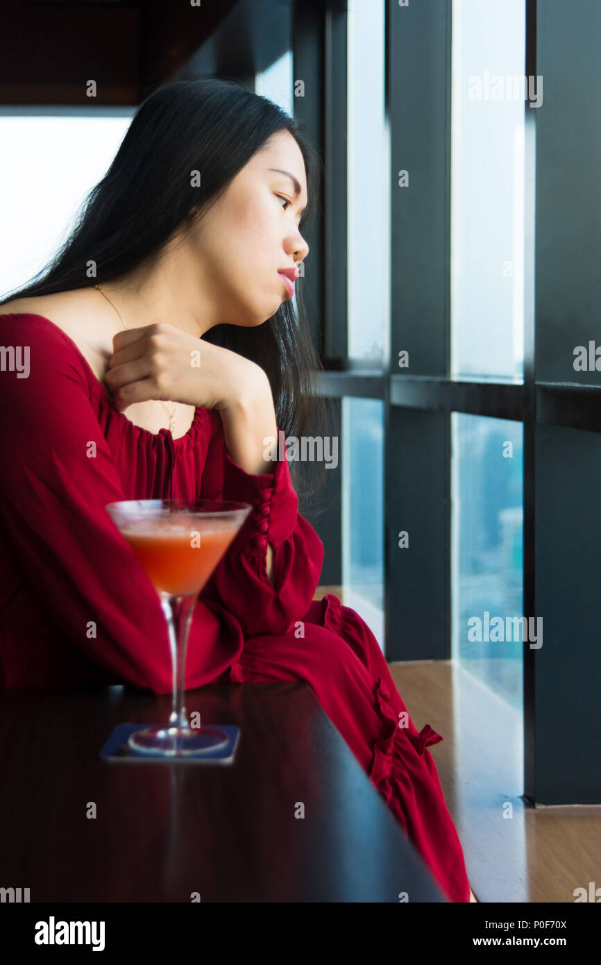 Malinconici ragazza avente un drink da soli in un bar Foto Stock