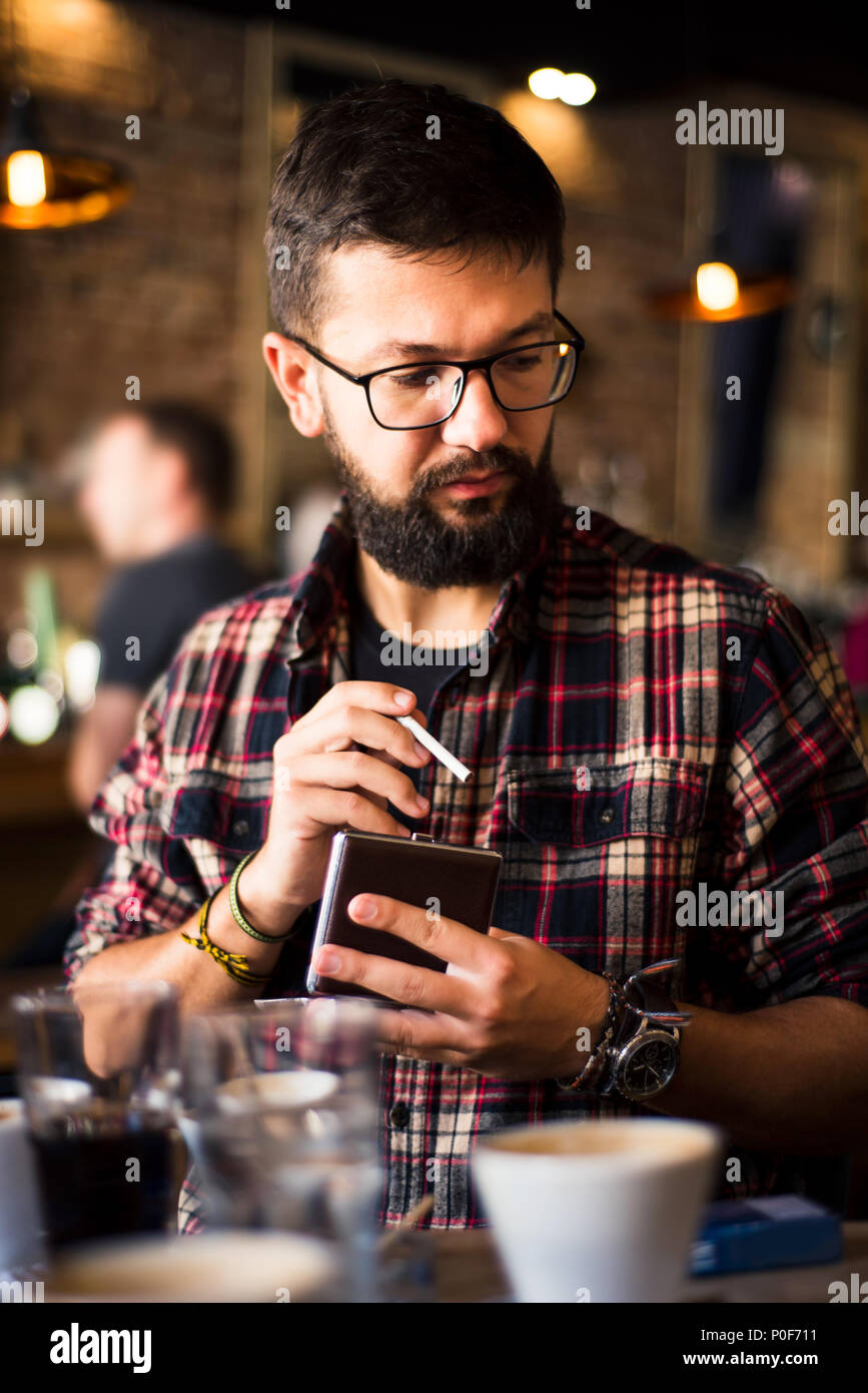 Tanga barbuto uomo in un bar caffetteria con un sigaro Foto Stock