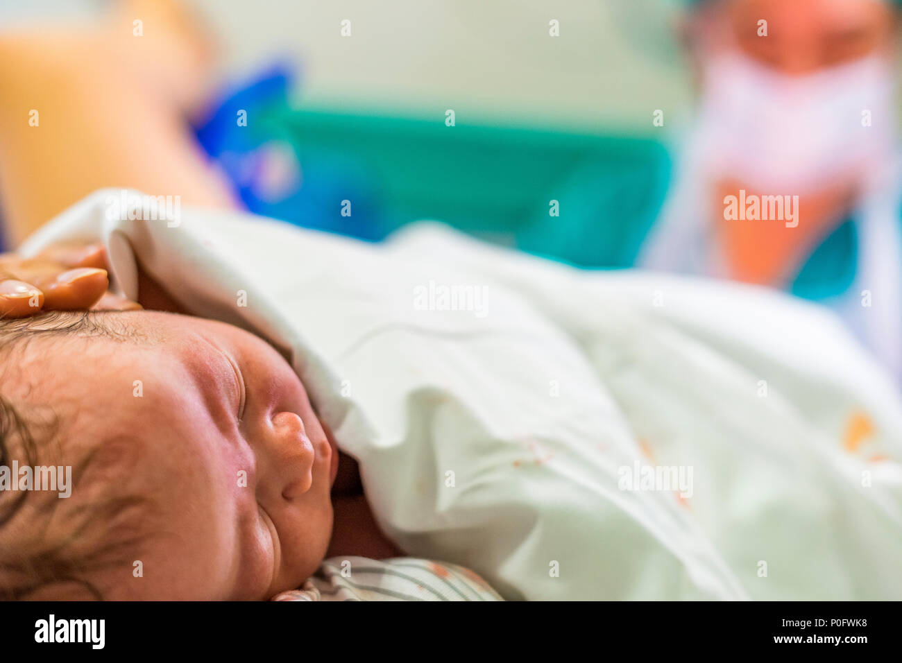 Carino neonato ragazzo solo dopo il parto e dottore in background Foto Stock