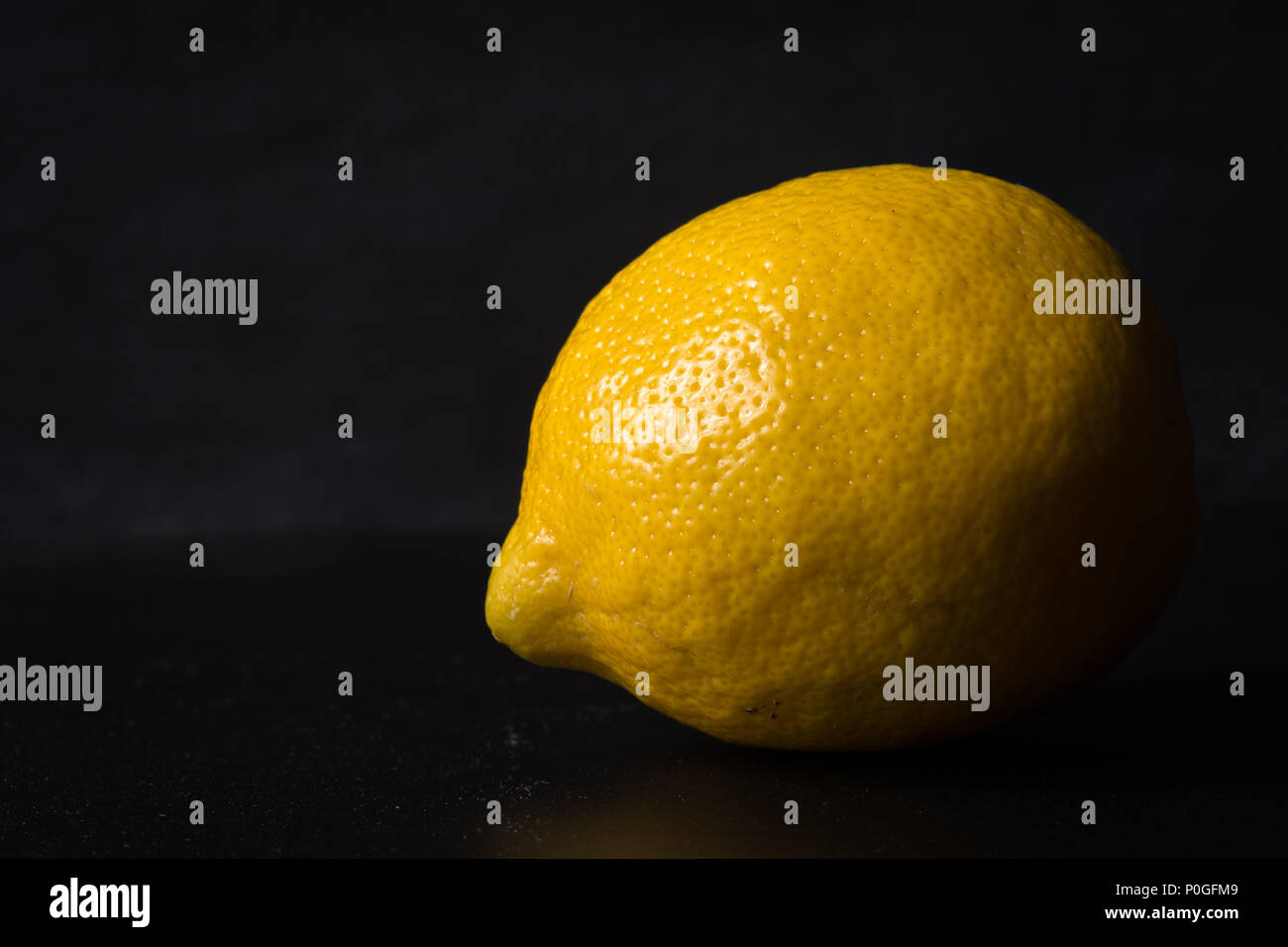 Limone isolato su sfondo scuro illuminato laterale che mostra la texture. Foto Stock