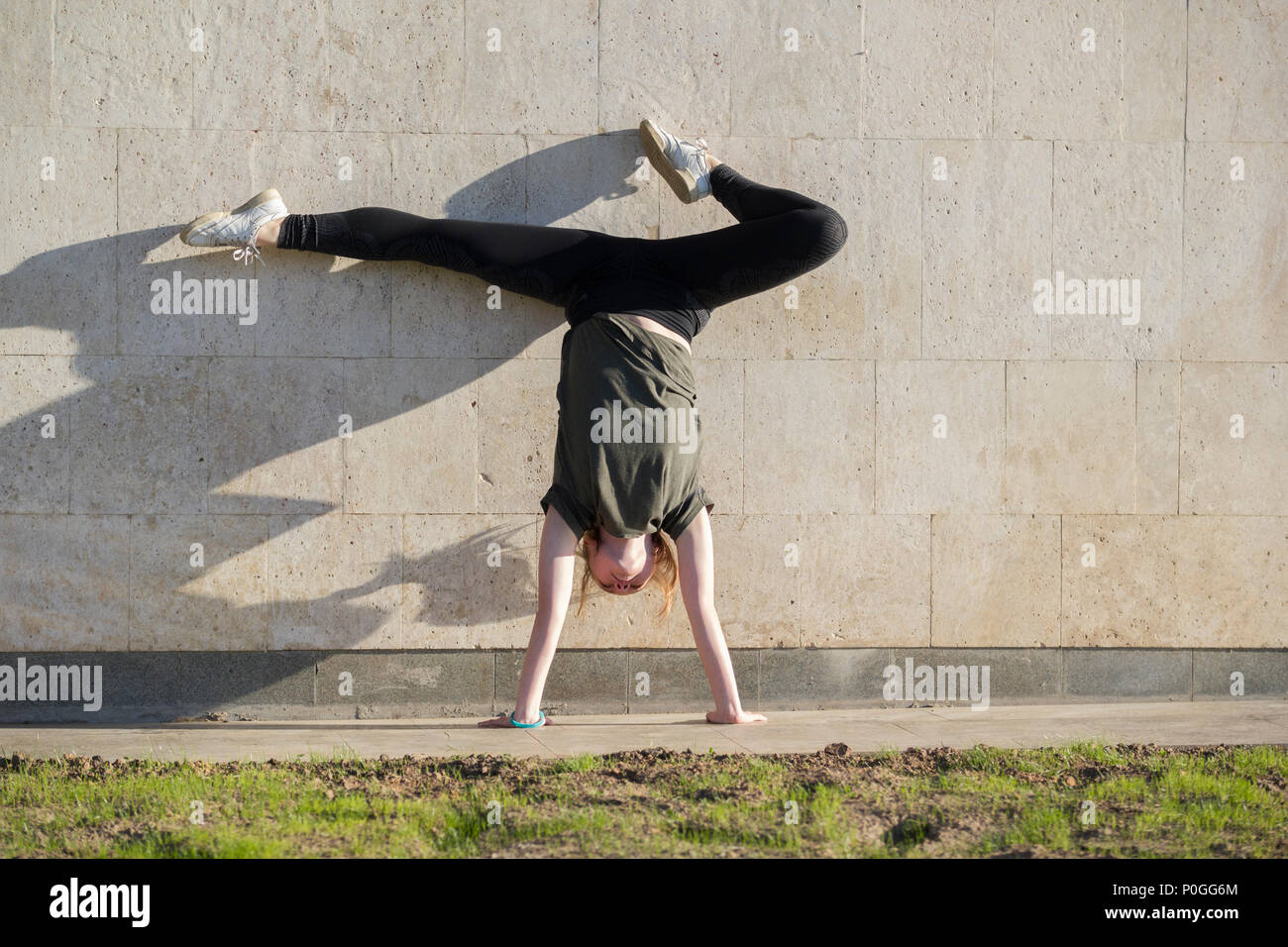 Giovani femmine handstand contro la parete esegue elementi acrobatico Foto Stock