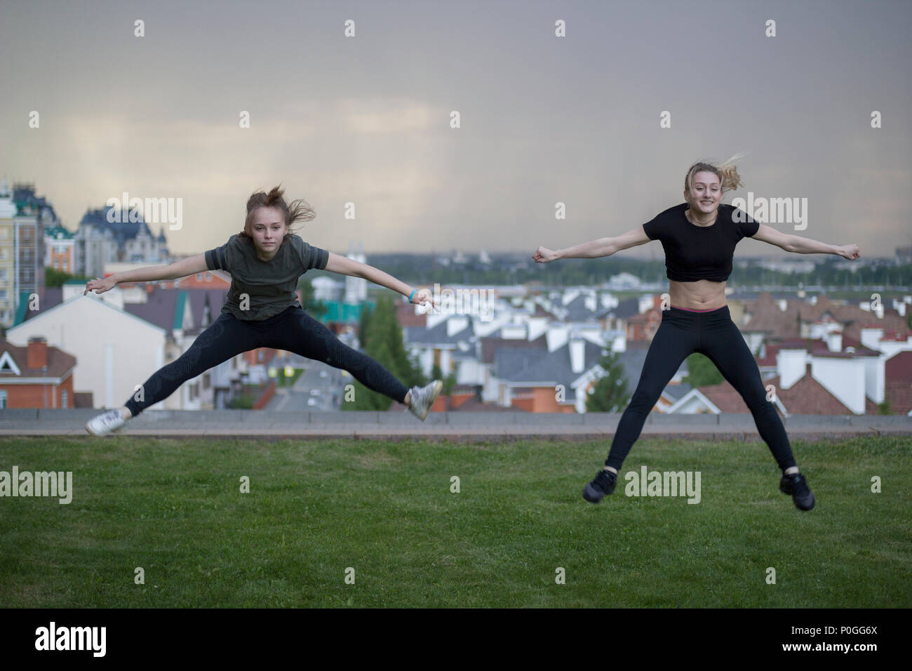 Due giovani donne ginnasti facendo acrobazie salta con il paesaggio sullo sfondo Foto Stock