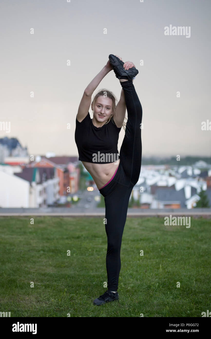 Flessibile di giovane donna in piedi sulla gamba in spago sull'erba Foto Stock