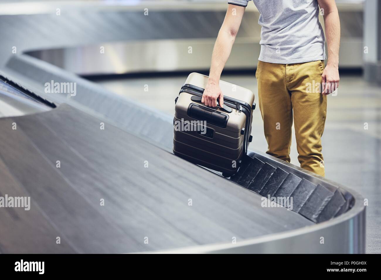 Man (traveler) prelievo di valigia dal reclamo bagagli in aeroporto. Foto Stock