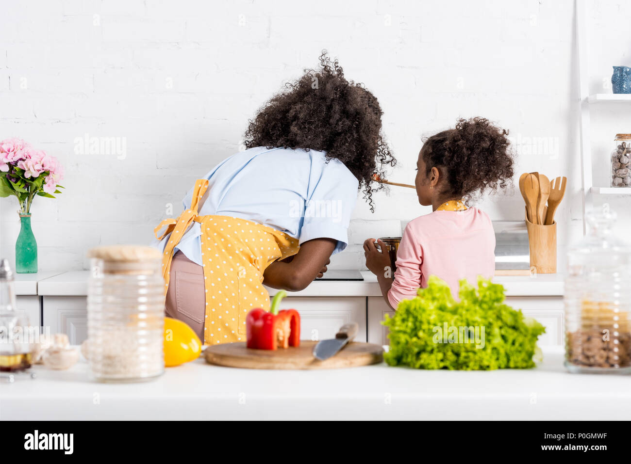 Vista posteriore di afro-americano di madre e bambino la cottura su cucina Foto Stock