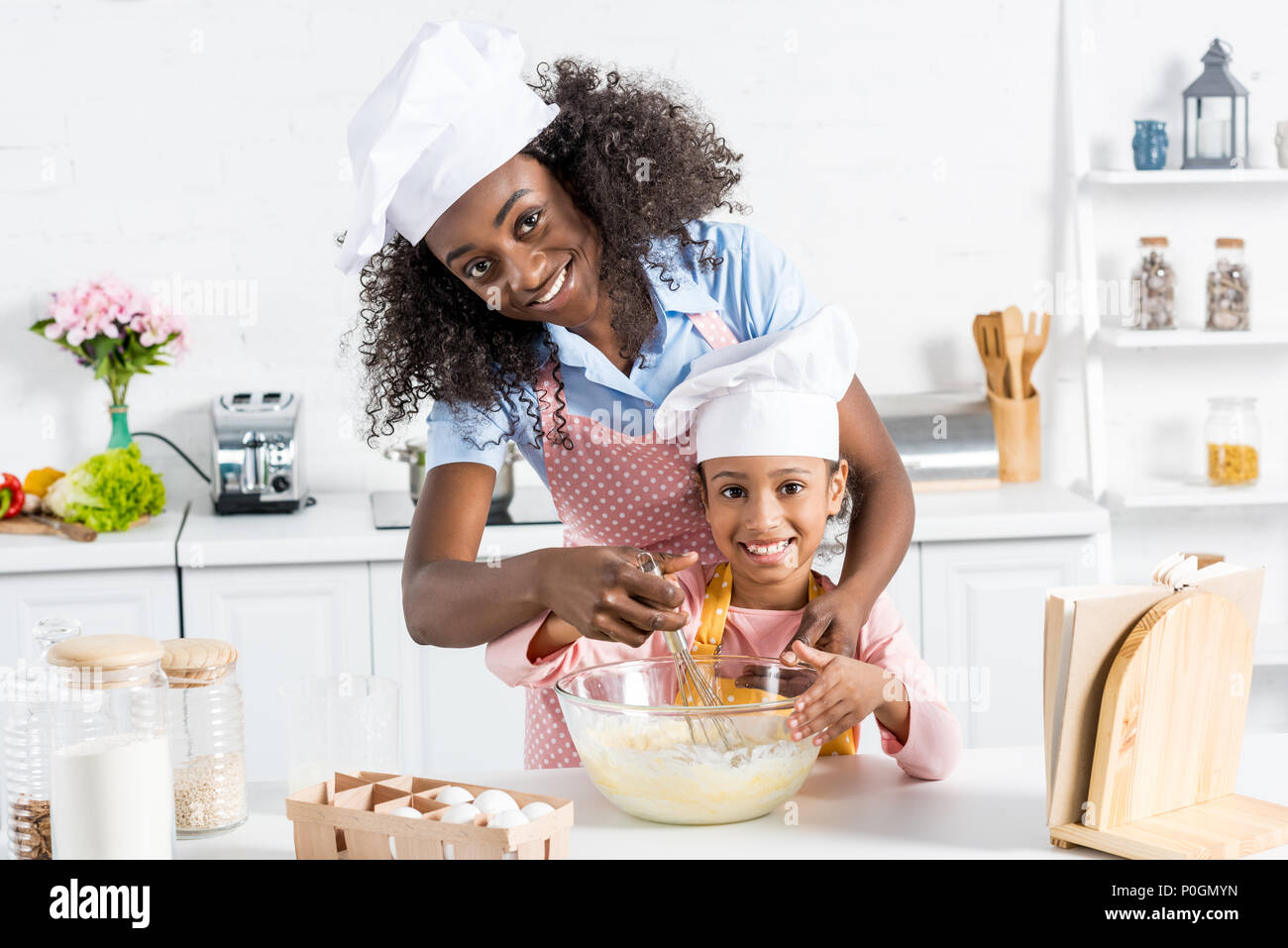 African American madre e figlia in chef cappelli pasta mescolando con una  frusta da cucina Foto stock - Alamy
