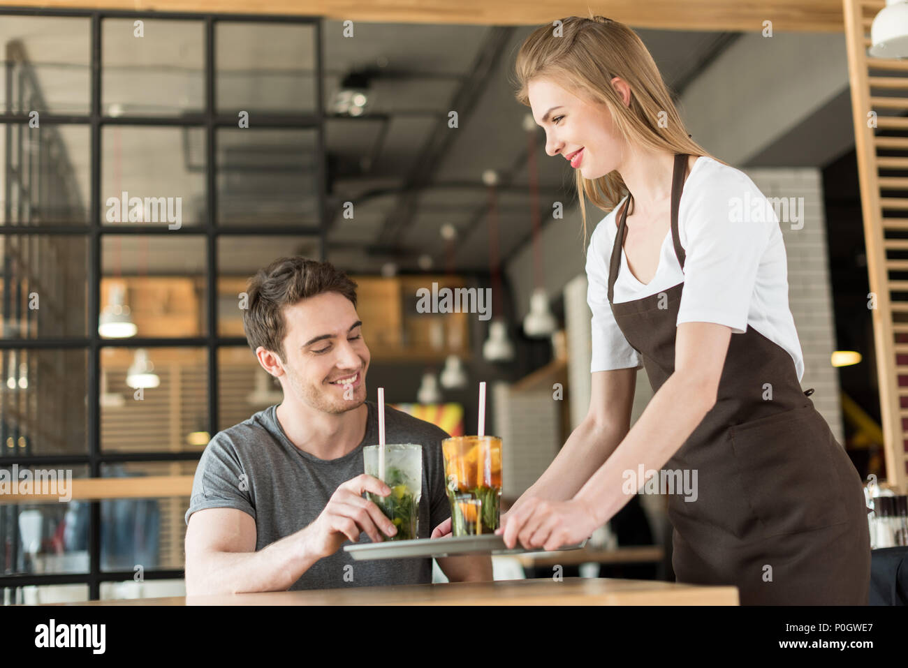 Sorridente cameriera del grembiule mettere ordine al client in cafe Foto Stock
