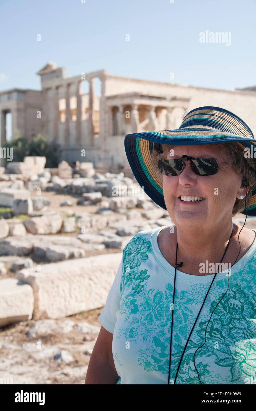 Senior donna nel cappello e occhiali da sole l'ascolto di una visita guidata alle rovine di Atene Foto Stock