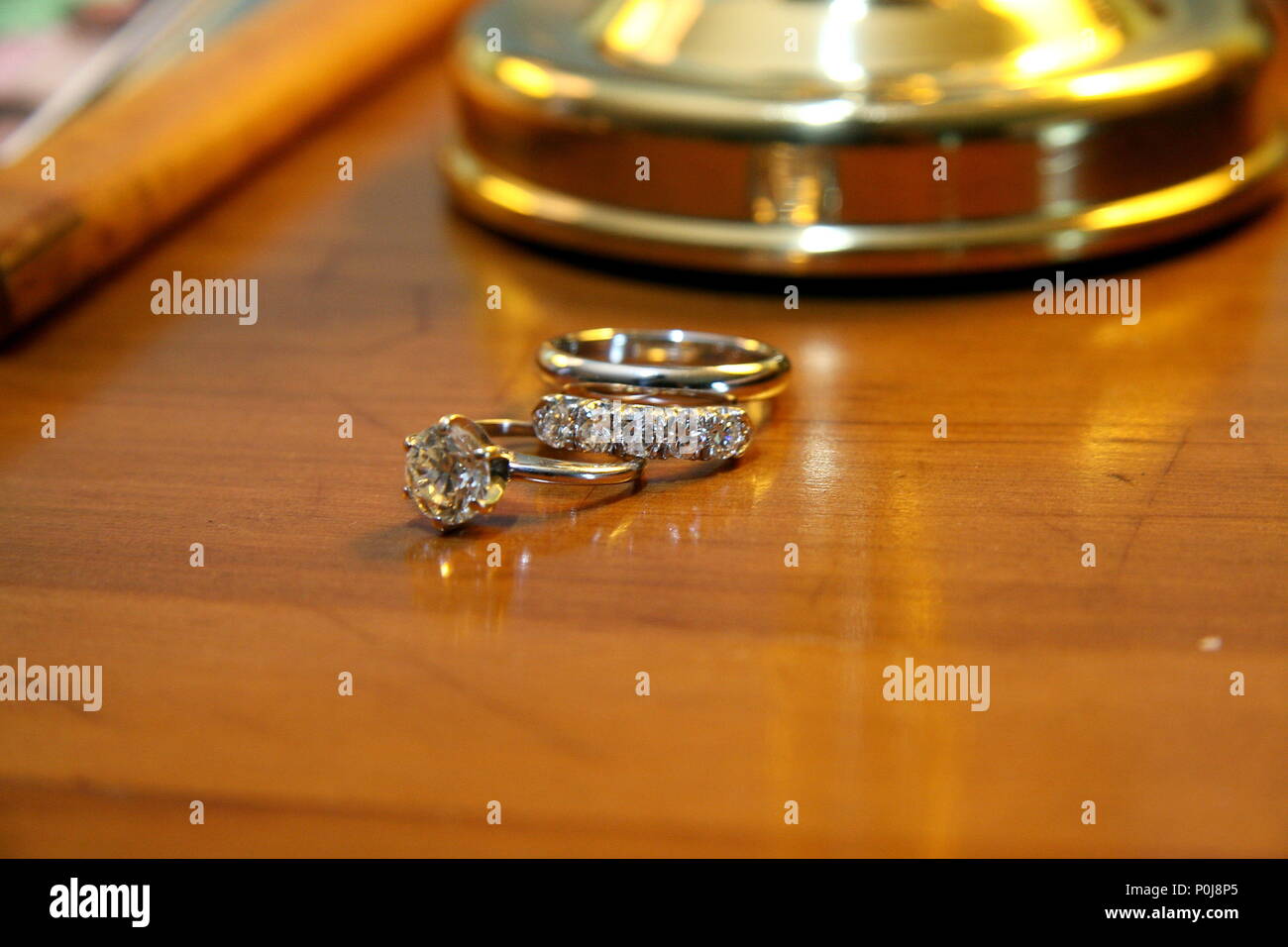Impegno anello diamante e due anelli di nozze sul comò pronto per il giorno del matrimonio cerimonia Foto Stock