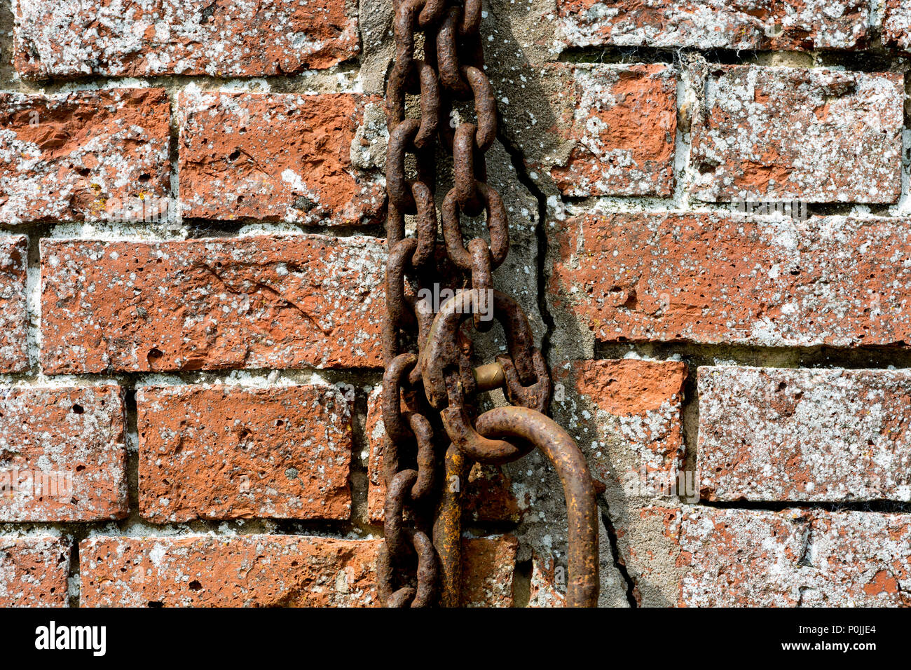 Vecchia catena e un muro di mattoni Foto Stock