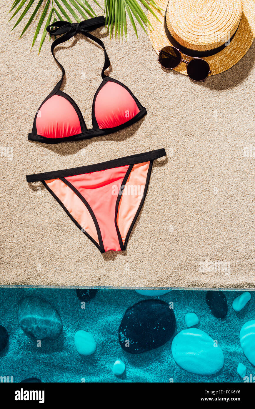 Vista superiore della elegante bikini rosa con accessori sulla spiaggia sabbiosa Foto Stock