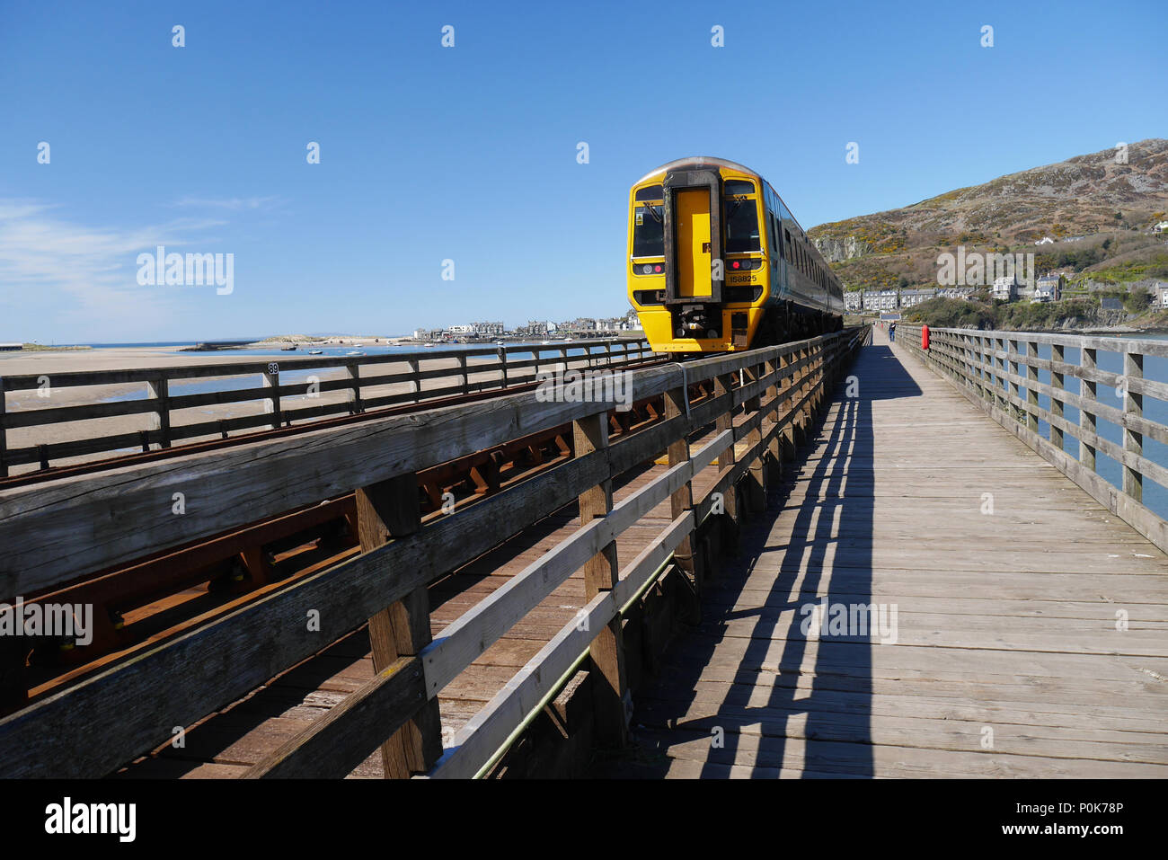 Afon-mawddach Barmouth, Wales, Regno Unito. Uomo che guarda un treno sul binario estuario/Piede-ponte. Foto Stock