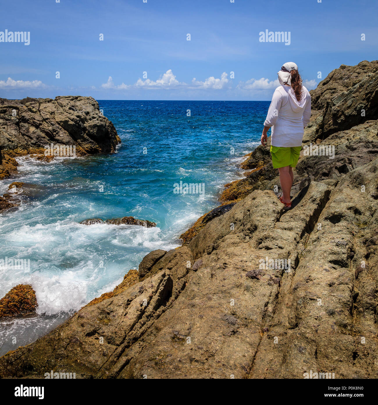 Una donna in piedi su una scogliera e la visione di navigare su di un isola del BVI Foto Stock