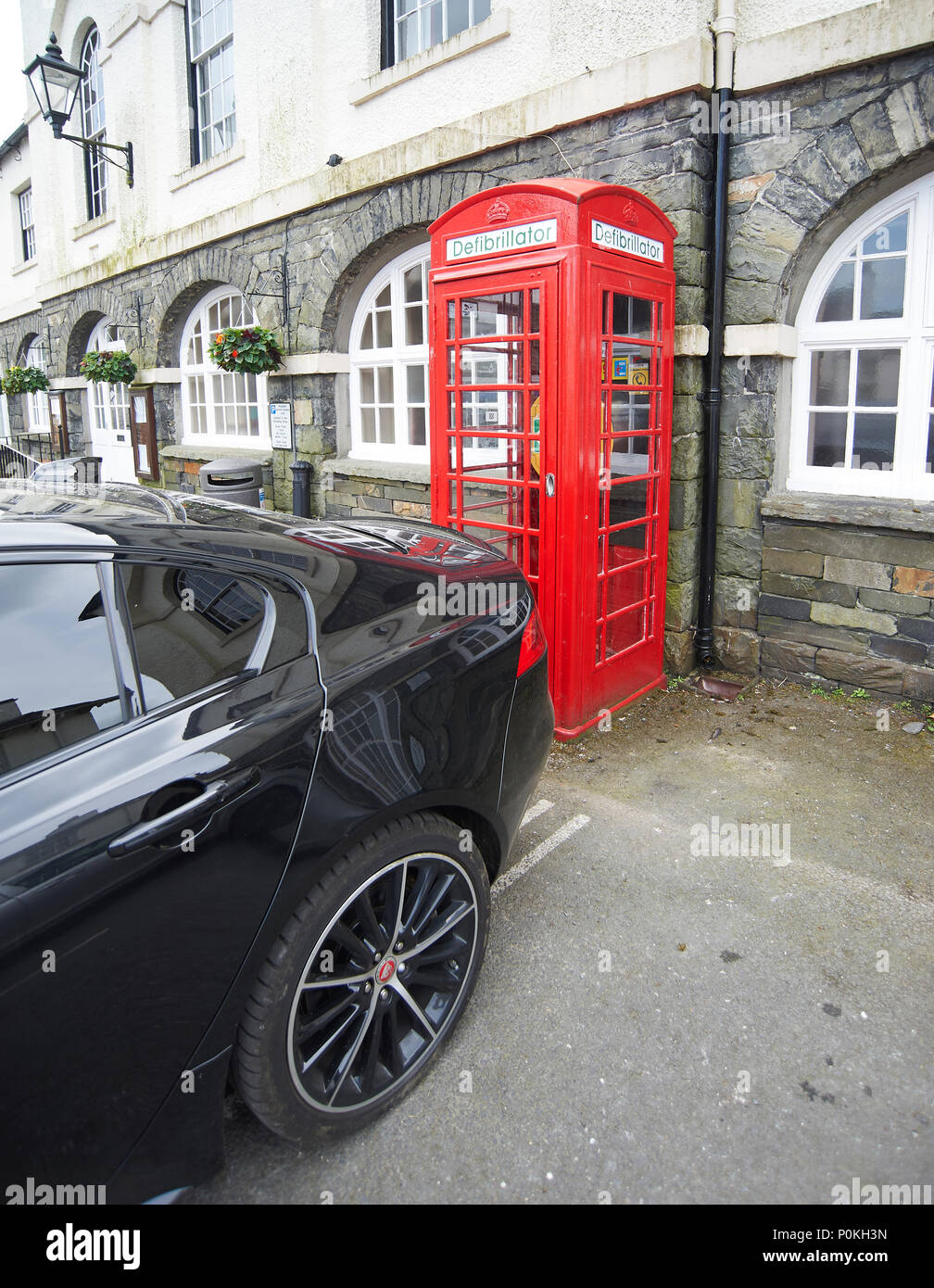 Donna parcheggiato il suo Jaguar auto così come al blocco di accesso di emergenza al villaggio defibrillatore in Hawkshead cumbria, Parco Nazionale del Distretto dei Laghi UK GB Foto Stock