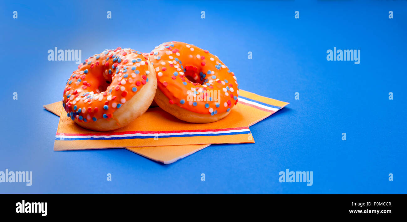 Celebrazione del re giorno nei Paesi Bassi. Vacanze divertenti. Arancione donats dolce su uno sfondo blu. Spazio libero per il testo Foto Stock