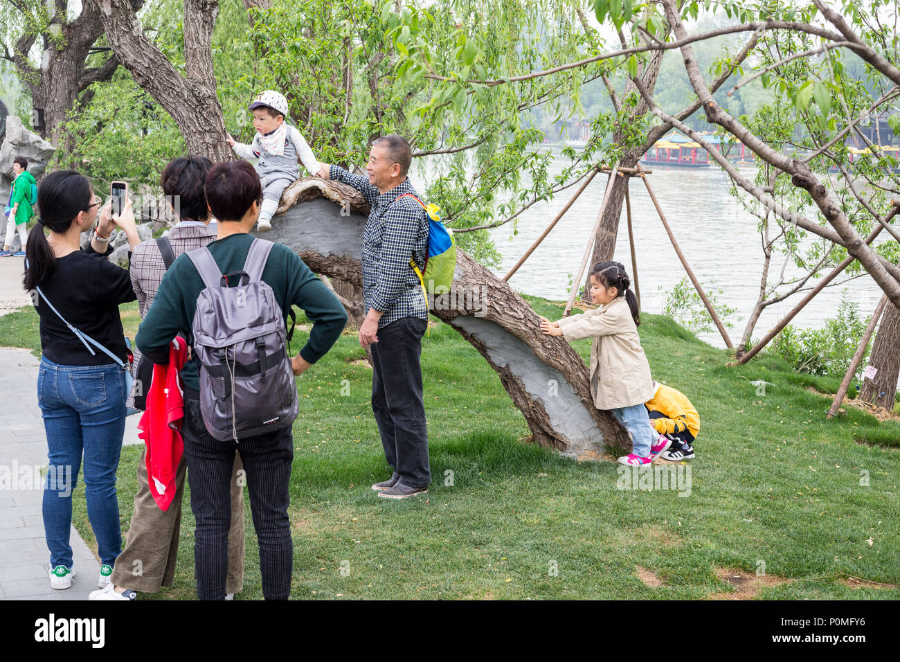 Yangzhou, Jiangsu, Cina. Famiglia cinese tenendo il telefono cellulare le foto della esile West Lake Park. Foto Stock