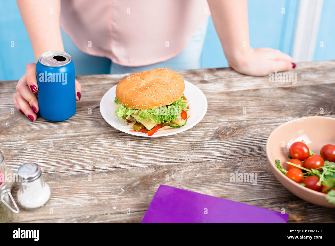Ritagliato colpo di Donna sovrappeso con soda drink permanente al piano portapaziente con il burger Foto Stock