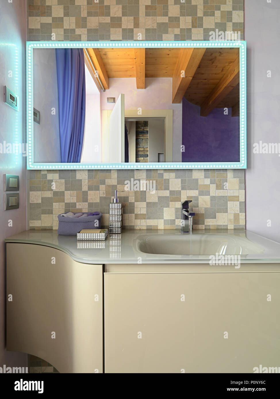 Bagno moderno interno in primo piano il lavandino Mobile lavandino integrato nel piano, specchio incorniciato di lampadine Foto Stock