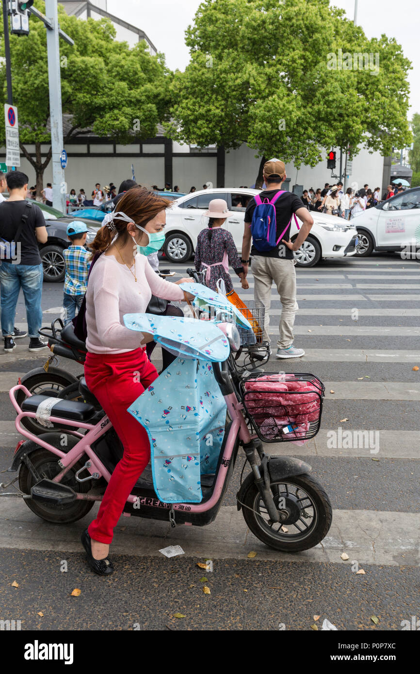 Suzhou, Jiangsu, Cina. Giovane donna sulla moto con una maschera per la respirazione. Foto Stock