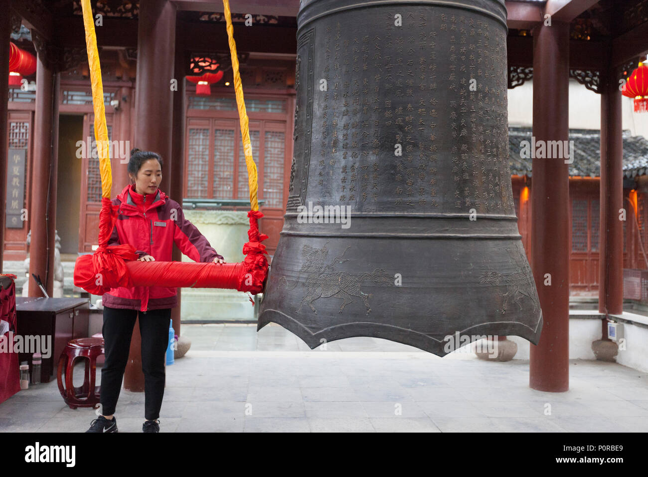Nanjing, Jiangsu, Cina. Giovane donna suonando il campanello nel Padiglione della campana del tempio confuciano complesso. Foto Stock